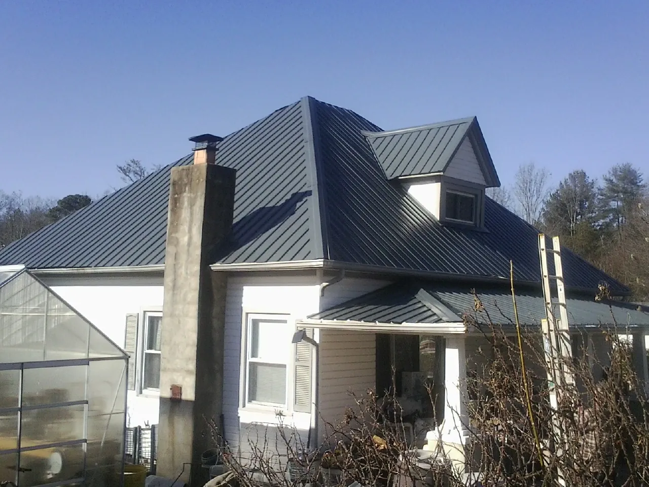 Dark blue standing seam metal roof on a white farmhouse with dormer — Slate & Tile Roof Repair by Roofing Brothers in Fountain Valley