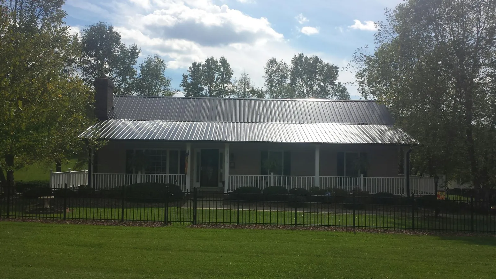 Gray metal roof on a brick ranch with a full width front porch — Gutter Guard Installation work by our crew in Fountain Valley