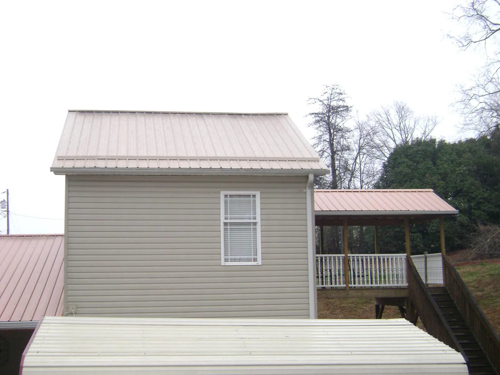 Tan metal roofs on a two story addition and attached porch, from a Roof Replacement job in Fountain Valley