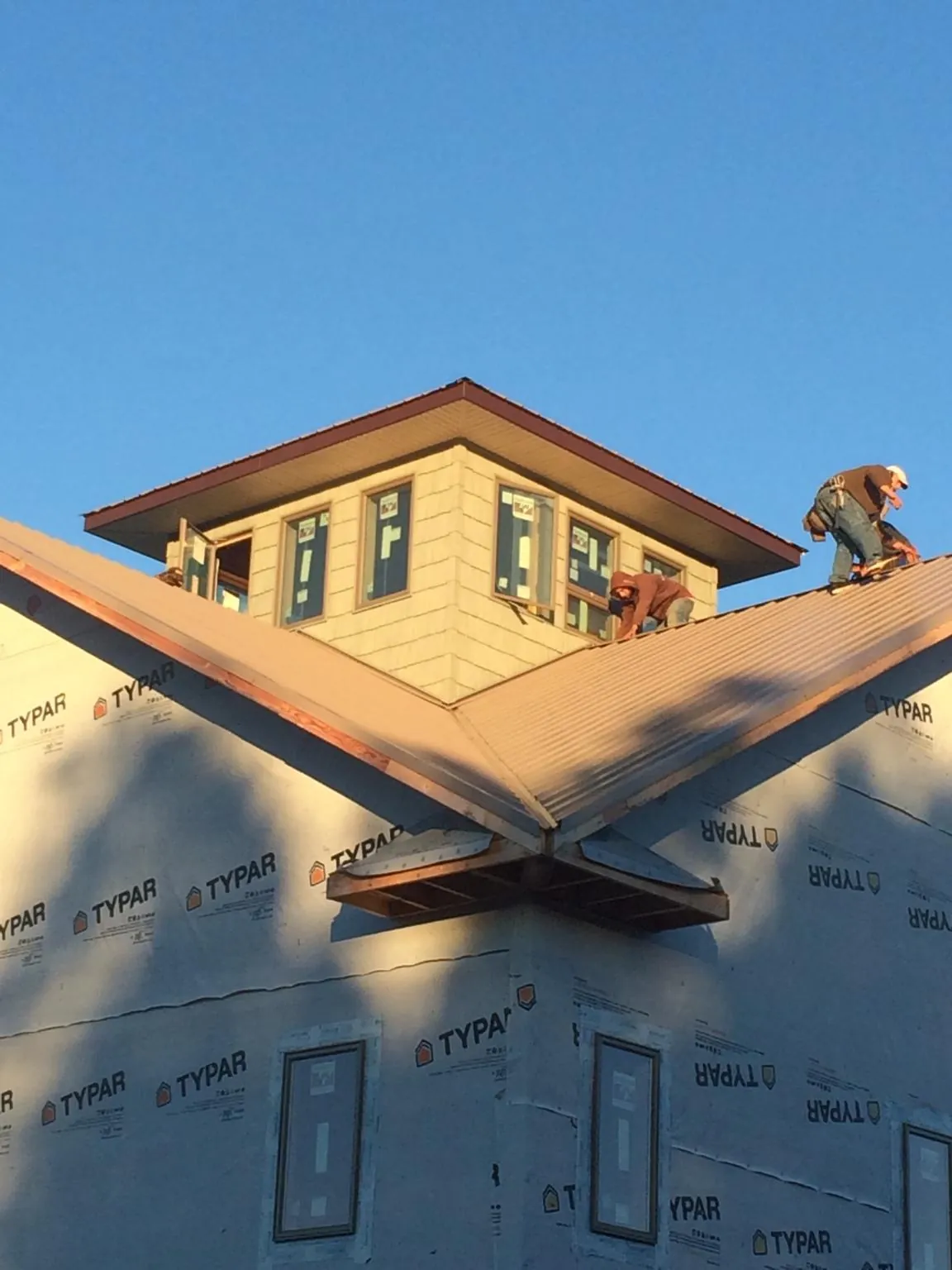 Roofers working around a rooftop cupola on a new metal roof at sunset — Roof Waterproofing in Fountain Valley by Roofing Brothers
